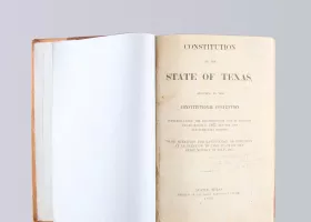 open book with the title "Constitution of the State of Texas"