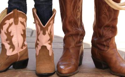 A pair of brown and pink cowboy boots standing next to a pair of brown leather cowboy boots.