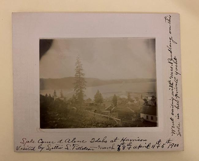 photograph in matting of a landscape of a lake with a tree in center, there is writing on the matting