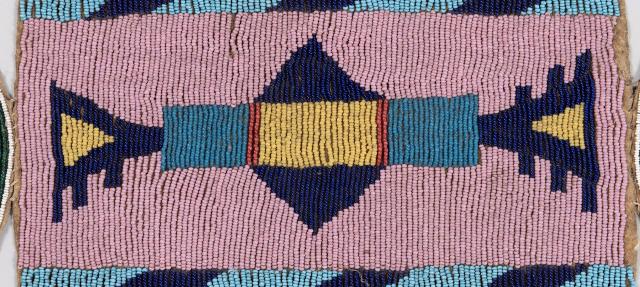 Rectangular beaded strip with geometric patterns in blue, dark blue, yellow, and red beads on a pink background; diagonal blue and dark blue bands border the top and bottom edges.