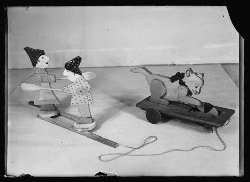 wooden toys, one of tow people with oars and one of a cat playing with a ball