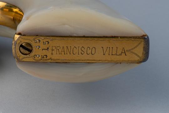 A close-up of a brass plate engraved with "FRANCISCO VILLA" and the numbers "315", attached to an ivory or cream-colored object with a smooth, curved surface.