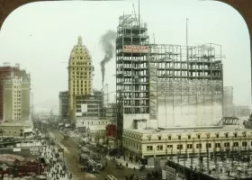 buildings being constructed, with a plume of industrial smoke in the background