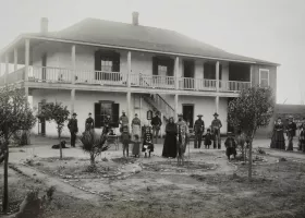 black and white photograph of a family standing in front of a white two-story building