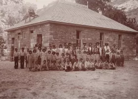 group of students standing in front of a stone building