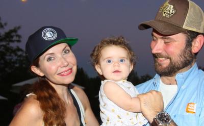 a woman in a baseball cap with a man in a baseball cap holding a baby