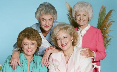 four women smiling fern in background blue backdrop