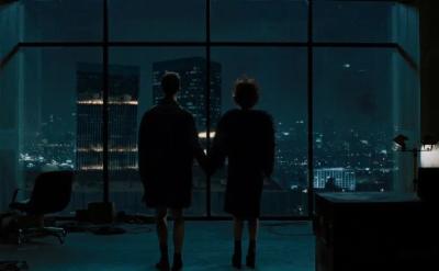two people standing in a dark room looking out of a skyscraper