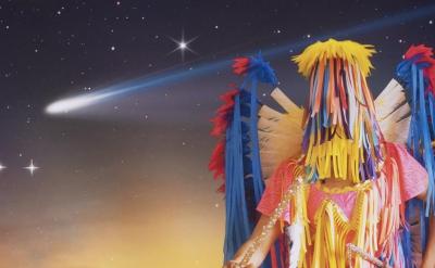 Figure wearing indigenous regalia in front of night sky
