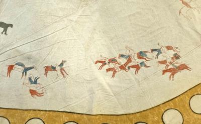 A painted scene on a tan surface shows figures on horseback, some holding weapons, in red, blue, and brown. Horses and riders appear in motion near a yellow, circular border at the bottom.