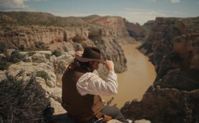 A man sitting on a rock looking at a river.