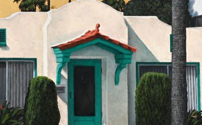 A small white stucco house with a red-tiled roof and teal trim on the door and windows, surrounded by neatly trimmed bushes, palm trees, and a partial view of a white vehicle in the foreground.