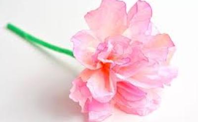 A close-up of a delicate, pink paper flower with a green stem, displayed against a white background.