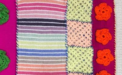 A variety of colorful crocheted and knitted fabric samples are lined up side by side, featuring stripes, green and orange floral motifs, pastel squares, and a zigzag blue pattern.