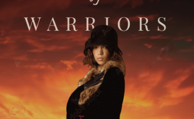 Book cover showing a young woman in a dark coat and hat standing confidently, with a group of warriors on horseback silhouetted against an orange sunset. Title reads "Daughter of Warriors" by Kimberly Kirkland Seidman.