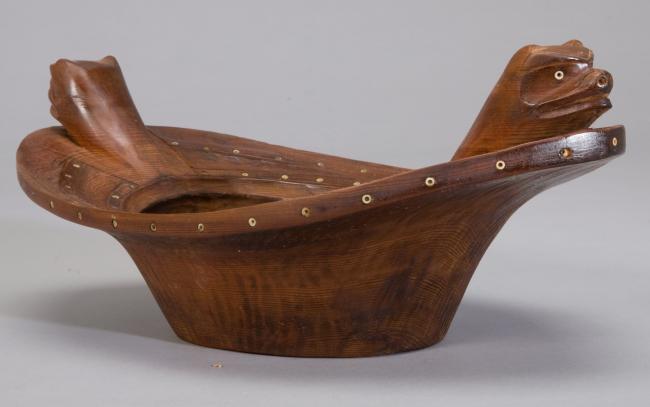 a wooden bowl with carved bear heads as handles