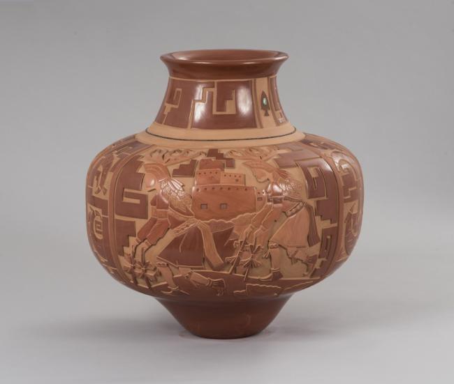 a ceramic vase with sculpted native american images