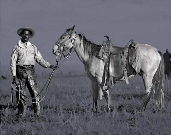 Vintage image of black cowboy leading horse
