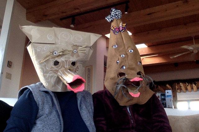 two people wear paper bag masks