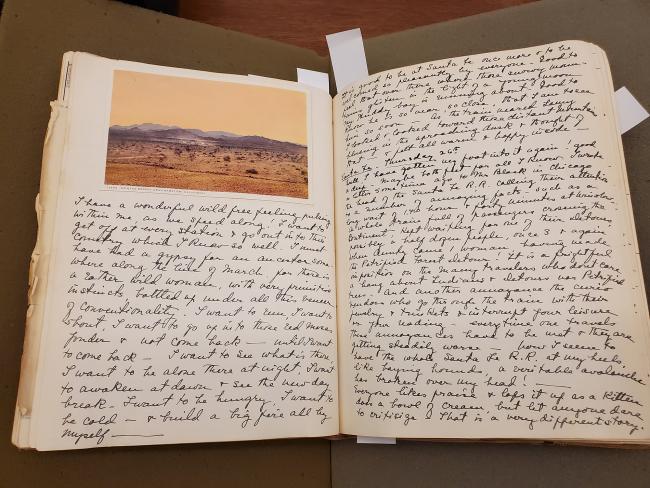 open notebook with picture of a desert landscape and dense hand writting on both pages