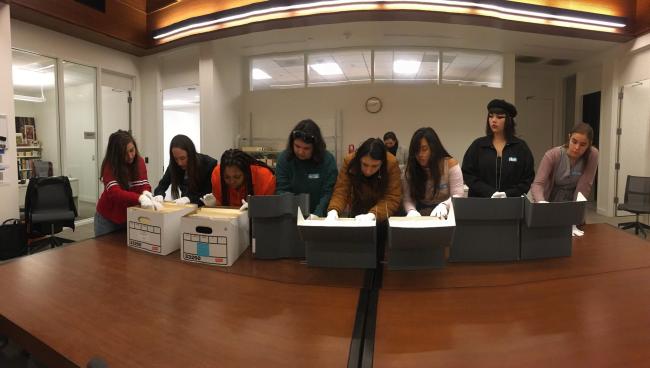 Students at library tables examining archival materials