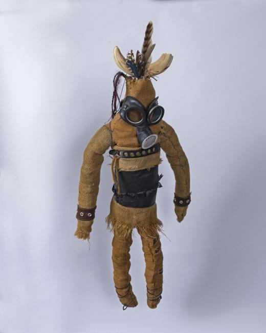 a doll with buckskin, feathers, and a gas mask
