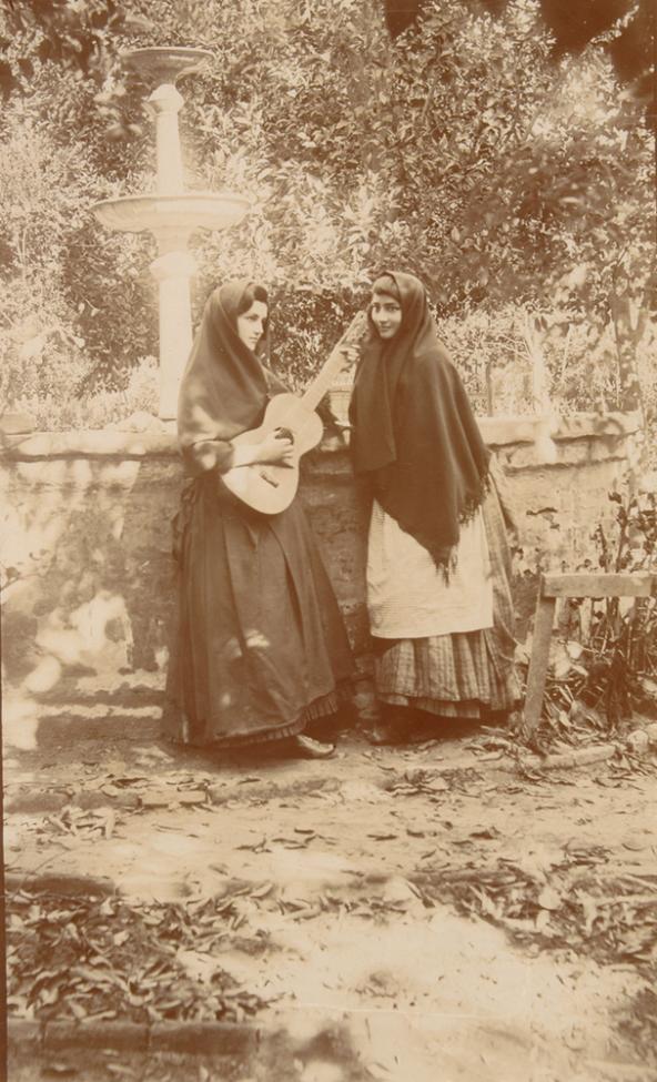 two women standing next to fountain one playing guitar