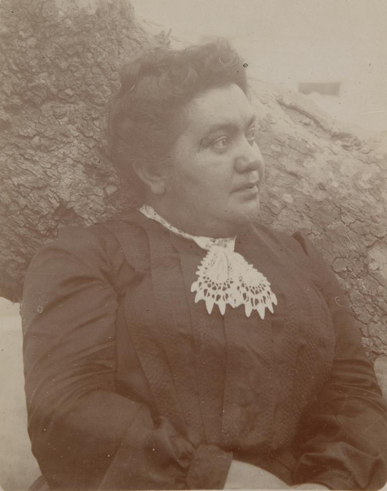 woman sitting next to a tree wearing a dress with a lace collar