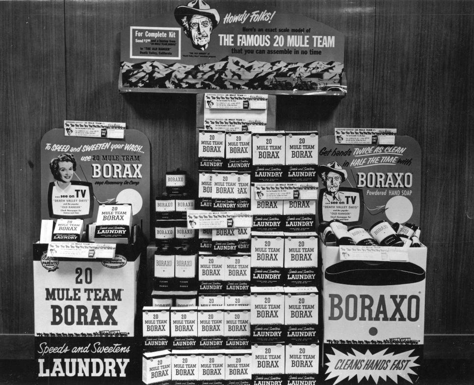 Black-and-white photo of a vintage store display with stacked boxes and signs promoting “20 Mule Team Borax” laundry products and “Boraxo” hand soap, including images of a woman and a cowboy mascot.