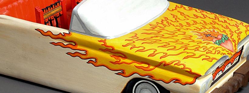 wooden sculpture of a low-rider car with fire and sacred heart symbolism