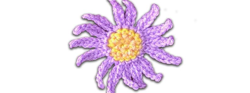crochet daisy made of purple yarn with a bright yellow center