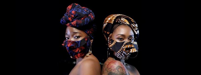 two african-american women in masks with a look of confidence pose with bare shoulders