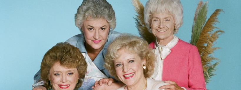 four women smiling fern in background blue backdrop