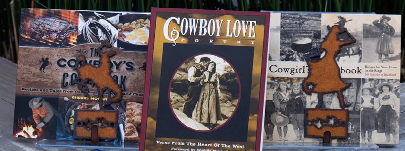 A collection of Western-themed books and cookbooks displayed on a table, featuring titles like "Cowboy Love Poetry," "The Cowboy's Cookbook," and "The All-American Cowboy Cookbook." Decorative cowboy-shaped ornaments are also present.