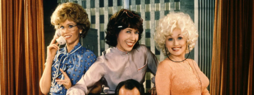 Three women from the 1980 movie "9 to 5" stand smiling behind a man tied to a chair. One woman is on the phone, one pours coffee into his mug, and one holds a notepad. They are in an office setting with striped curtains.