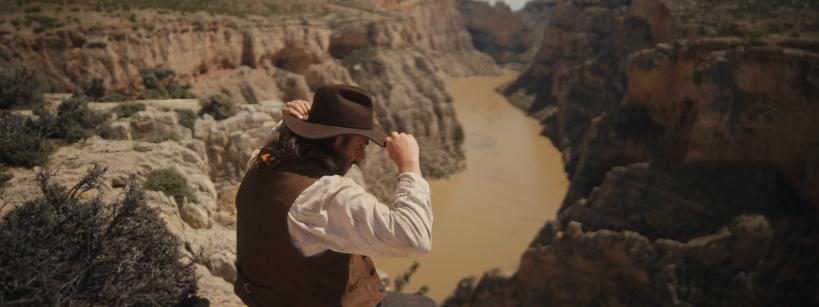 A man sitting on a rock looking at a river.