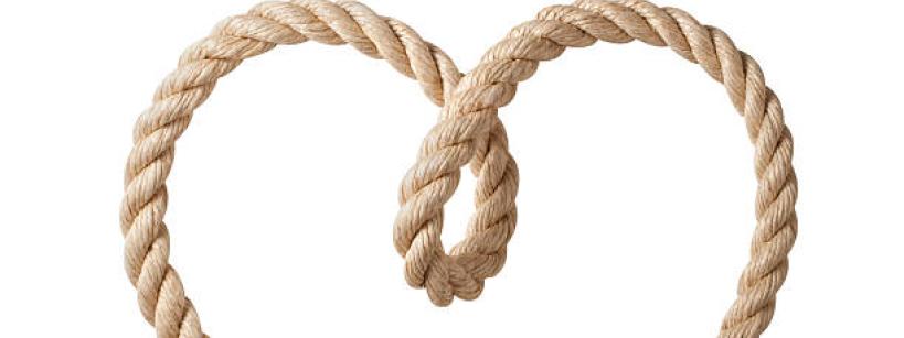 A brown rope twisted into the shape of a heart, with the ends crossing at the bottom, on a white background.