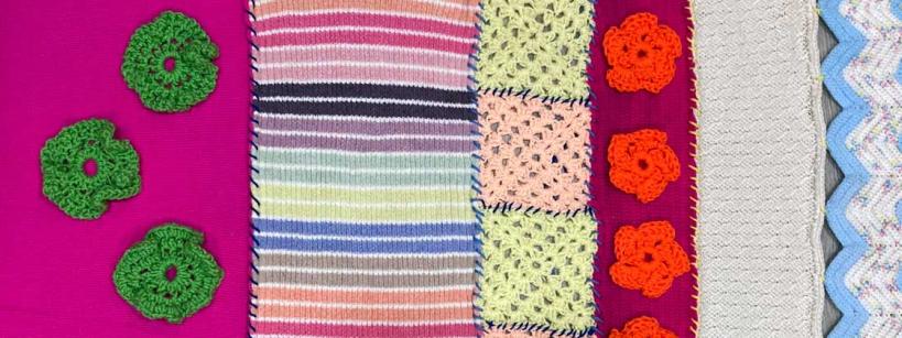 A variety of colorful crocheted and knitted fabric samples are lined up side by side, featuring stripes, green and orange floral motifs, pastel squares, and a zigzag blue pattern.