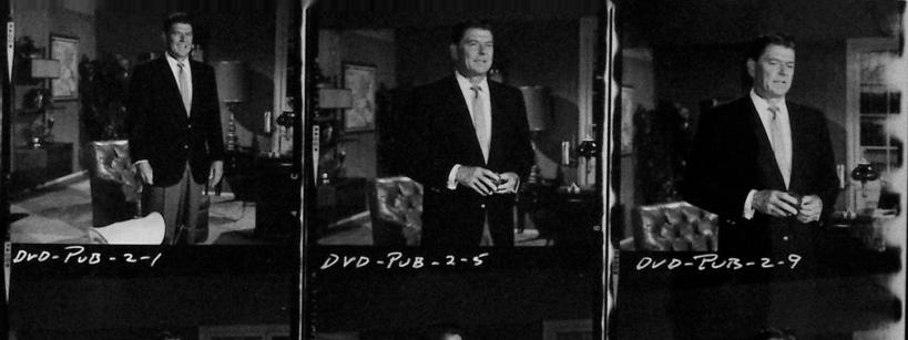 A black-and-white contact sheet showing six photos of a man in a suit, standing and holding objects in a living room setting. Handwritten labels and numbers are visible above and below the images.