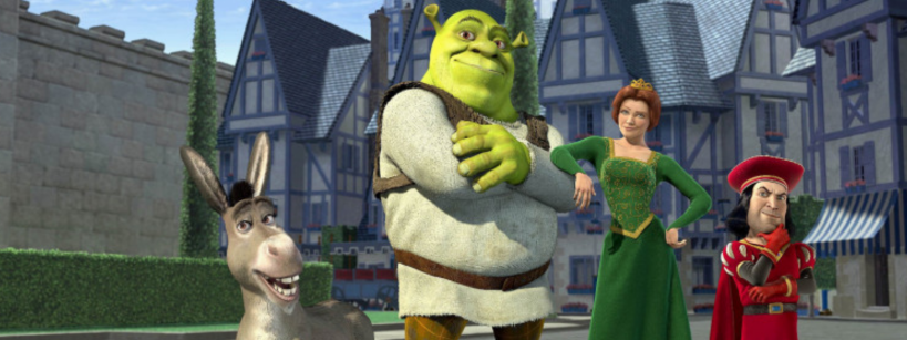 Animated characters Donkey, Shrek, Fiona, and Lord Farquaad stand posing confidently in front of medieval-style buildings and a castle wall in daylight.